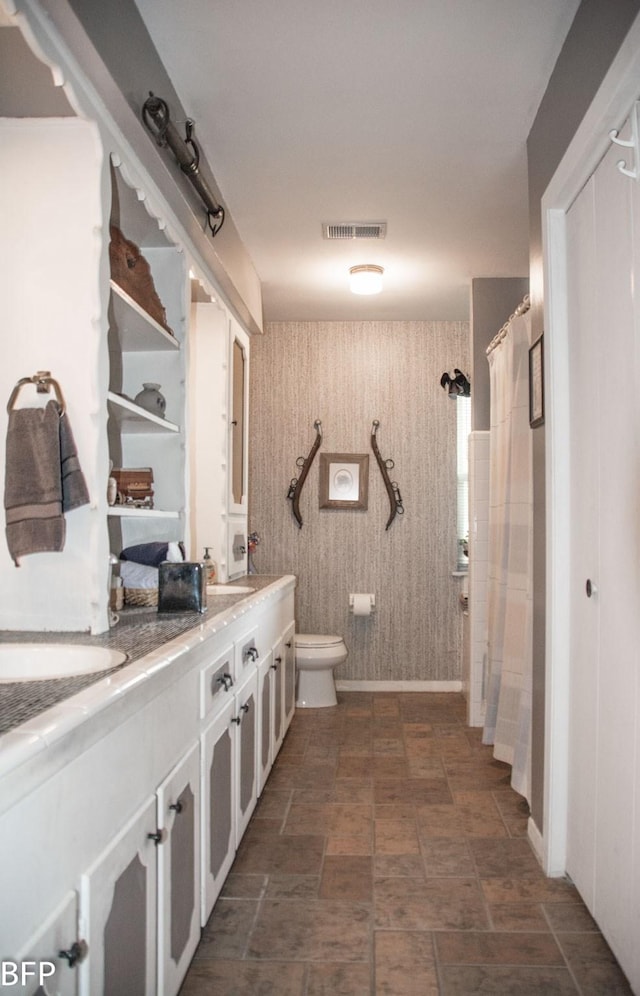 bathroom with double vanity, toilet, curtained shower, and visible vents