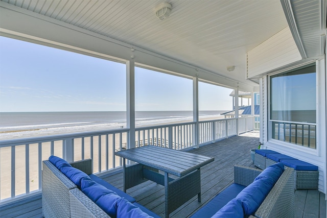 sunroom with an outdoor hangout area and view of water and beach