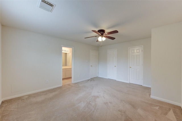 unfurnished bedroom featuring light carpet, ensuite bath, a ceiling fan, baseboards, and visible vents