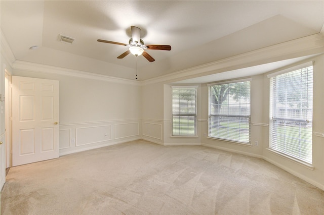 unfurnished room featuring a tray ceiling, light colored carpet, plenty of natural light, and ceiling fan