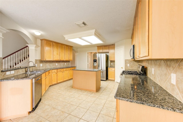 kitchen featuring visible vents, ornate columns, arched walkways, a sink, and stainless steel appliances