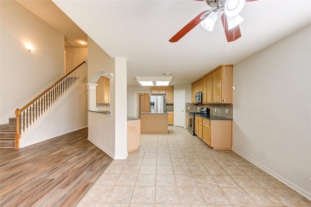 kitchen featuring baseboards, ceiling fan, stainless steel appliances, and tasteful backsplash