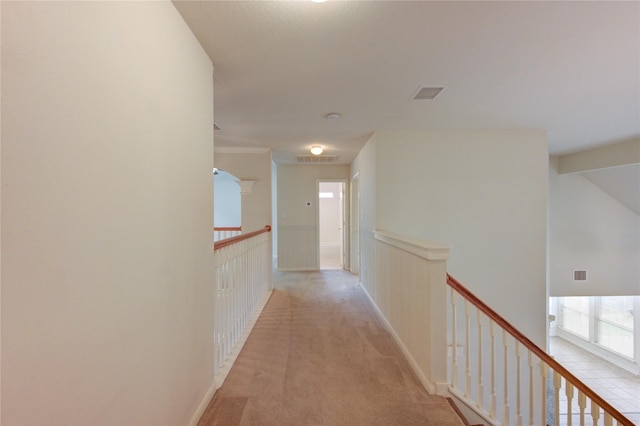 corridor featuring an upstairs landing, light carpet, and visible vents