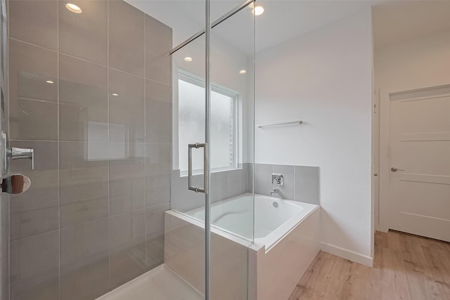 full bath with a bath, a shower stall, baseboards, and wood finished floors