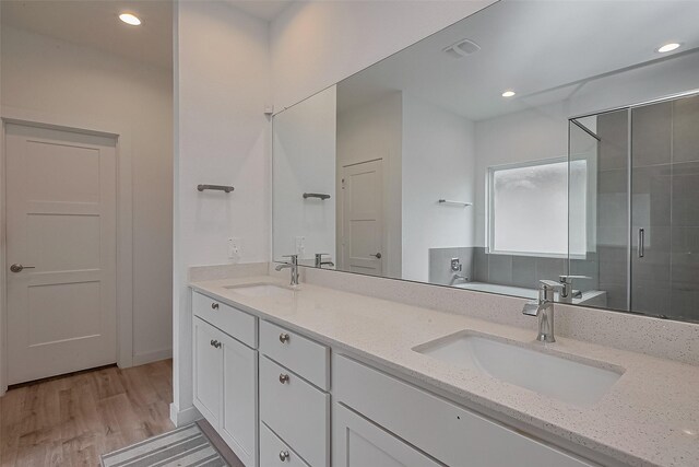 full bathroom with a shower stall, wood finished floors, a sink, and double vanity