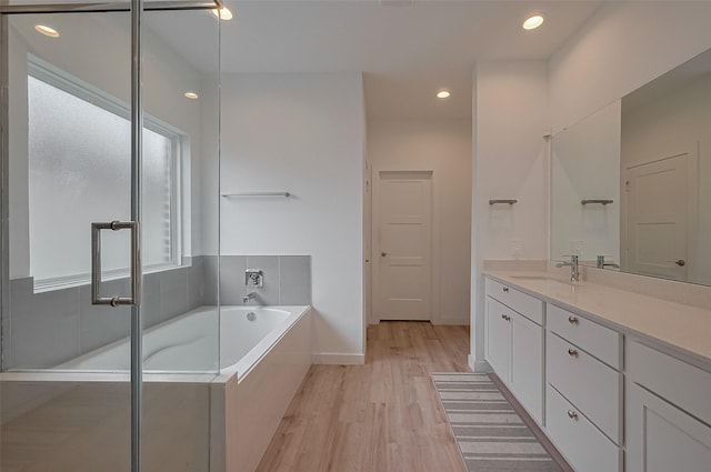 full bathroom with a garden tub, vanity, wood finished floors, and recessed lighting