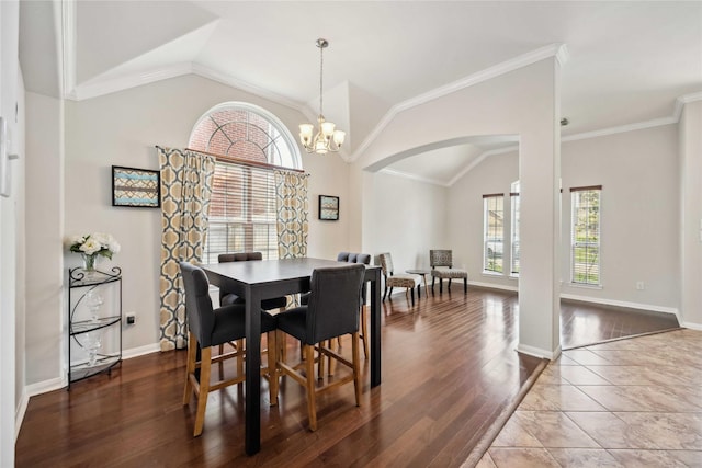 dining area with arched walkways, baseboards, an inviting chandelier, lofted ceiling, and wood finished floors