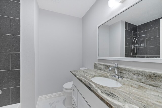 full bathroom featuring a tile shower, vanity, baseboards, toilet, and marble finish floor