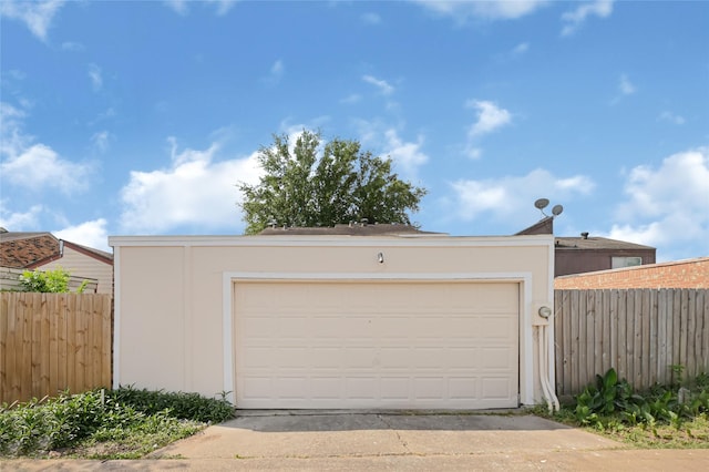 garage with fence and concrete driveway