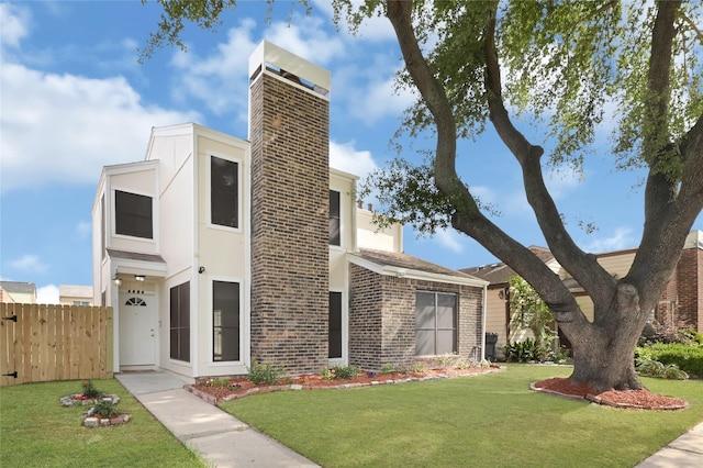 contemporary house with fence, a front lawn, brick siding, stucco siding, and a chimney