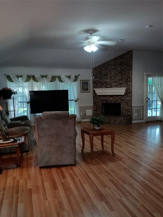 living area featuring ceiling fan, wood finished floors, lofted ceiling, and a fireplace