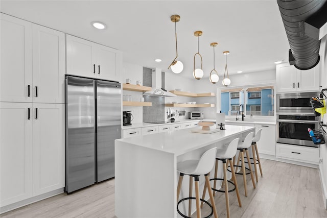 604 Calico Jack Cv, Galveston, TX 77554 - kitchen featuring open shelves, light wood-style floors, appliances with stainless steel finishes, and wall chimney range hood
