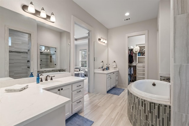 1406 Amber Cv, Willis, TX 77378 - full bathroom featuring a tile shower, two vanities, a bath, recessed lighting, and a walk in closet