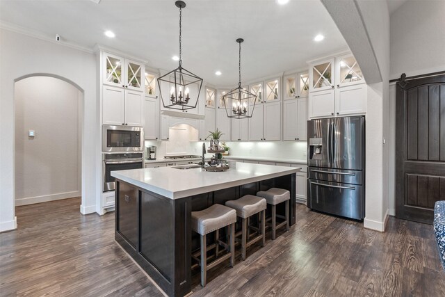 1406 Amber Cv, Willis, TX 77378 - kitchen with stainless steel appliances, arched walkways, a center island with sink, baseboards, and crown molding