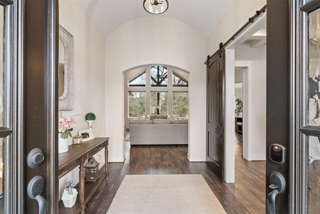 1406 Amber Cv, Willis, TX 77378 - entryway with a barn door, baseboards, dark wood finished floors, lofted ceiling, and arched walkways