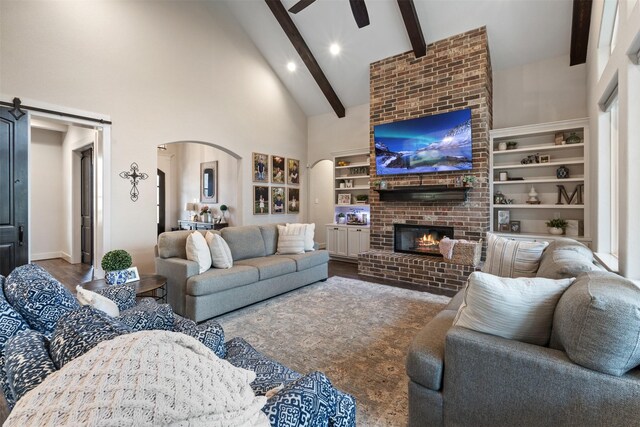 1406 Amber Cv, Willis, TX 77378 - living room featuring arched walkways, high vaulted ceiling, beamed ceiling, a brick fireplace, and a ceiling fan