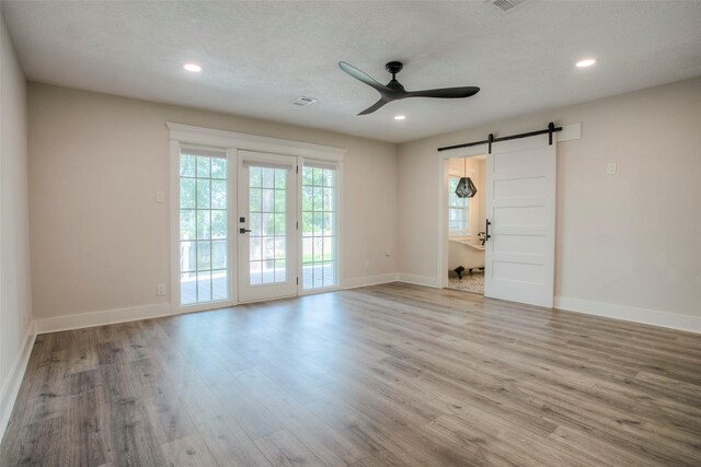 unfurnished room featuring a barn door, wood finished floors, ceiling fan, and recessed lighting