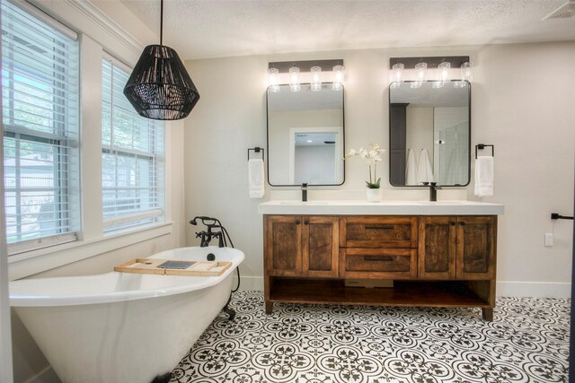 full bathroom featuring a freestanding bath, a textured ceiling, baseboards, and visible vents
