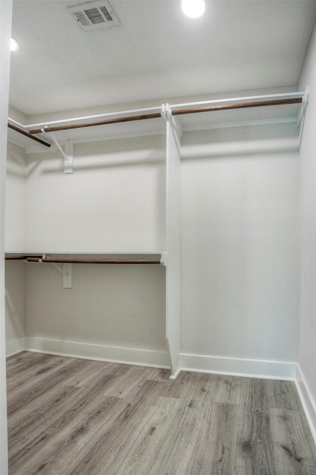 spacious closet featuring wood finished floors and visible vents