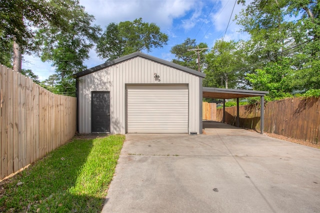 garage featuring driveway, fence, and a detached garage