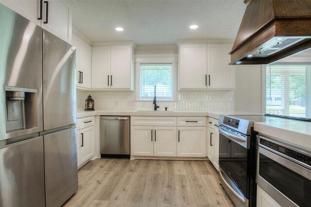 kitchen featuring light countertops, a sink, stainless steel appliances, and custom range hood