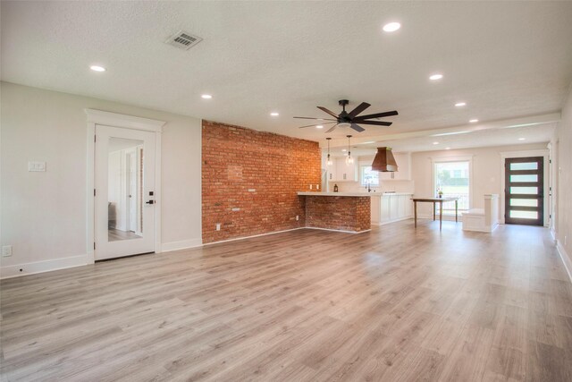 unfurnished living room featuring light wood-type flooring, ceiling fan, baseboards, visible vents, and recessed lighting