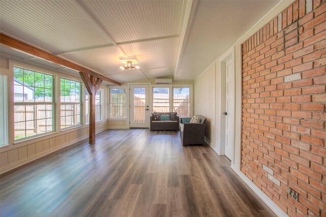 sunroom with brick wall, a wealth of natural light, an AC wall unit, and wood finished floors