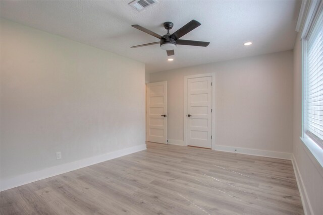 empty room featuring a ceiling fan, light wood finished floors, baseboards, visible vents, and recessed lighting