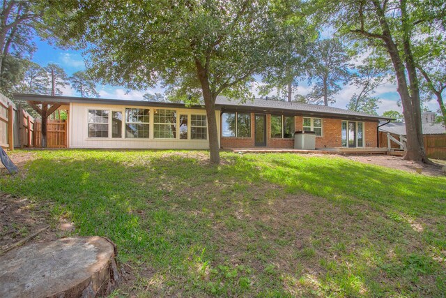back of house featuring fence, brick siding, and a yard