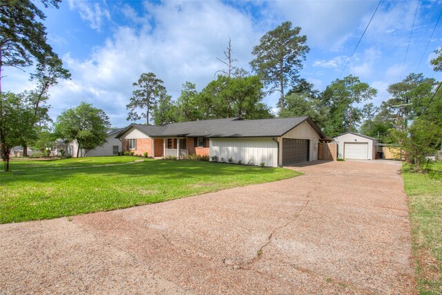 ranch-style house featuring a detached garage, a shingled roof, a front yard, and concrete driveway