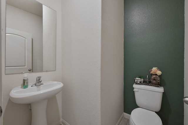 half bathroom featuring baseboards and toilet