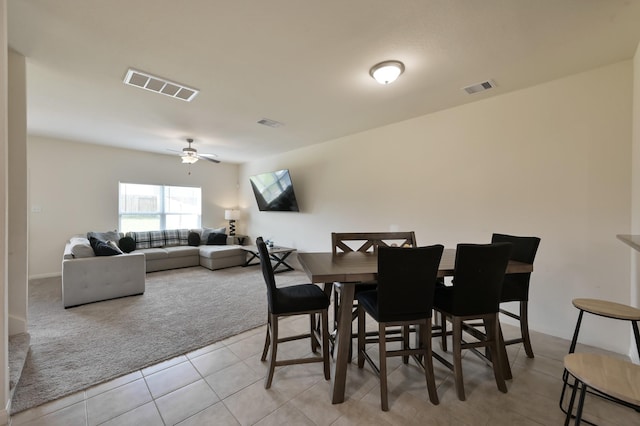 dining room with light carpet, a ceiling fan, visible vents, and light tile patterned flooring