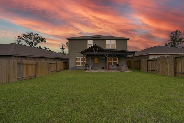 back of property at dusk featuring a fenced backyard, a lawn, an outdoor hangout area, and a patio