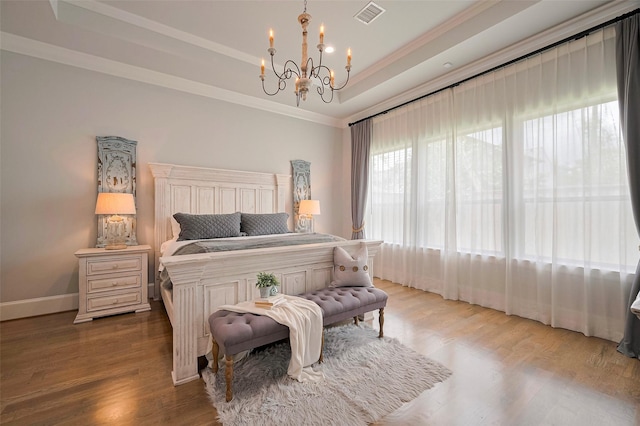 bedroom with a tray ceiling, a chandelier, crown molding, wood finished floors, and baseboards