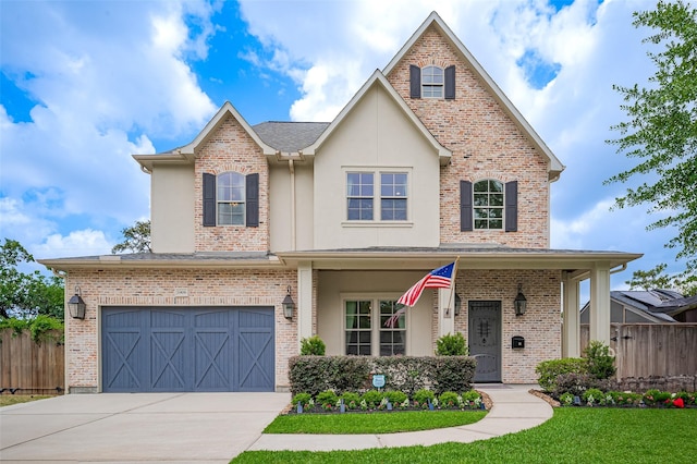 view of front of house featuring driveway, stucco siding, an attached garage, brick siding, and a porch