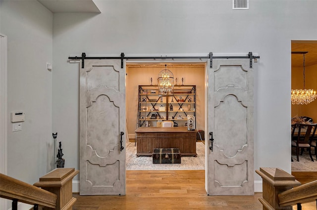 entryway with a barn door, a chandelier, and wood finished floors