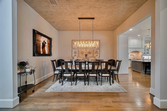 dining room featuring a chandelier, baseboards, and wood finished floors