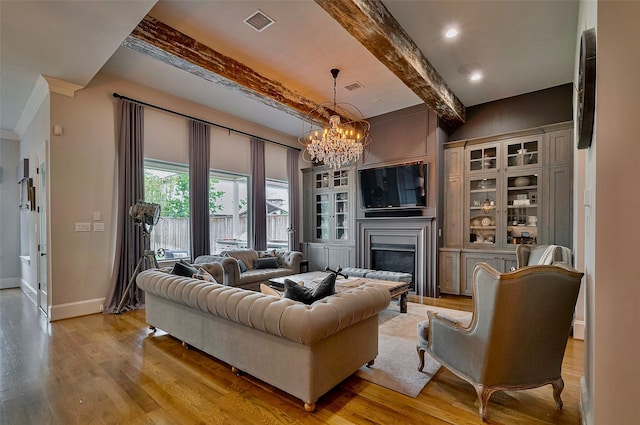 living room featuring a chandelier, light wood-style flooring, beamed ceiling, a fireplace, and baseboards
