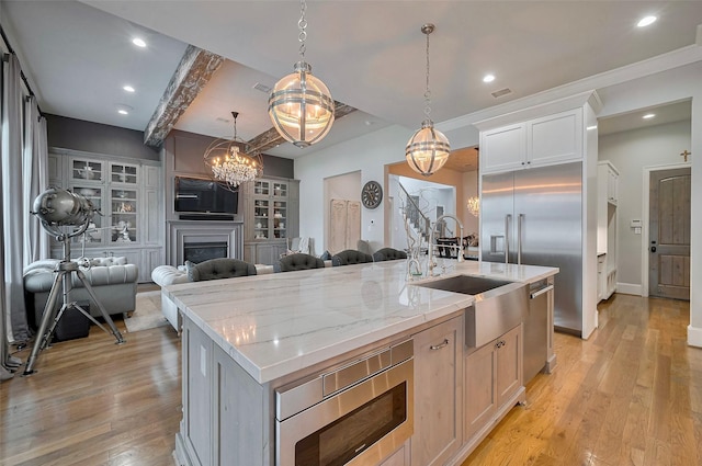 kitchen featuring a chandelier, appliances with stainless steel finishes, a sink, open floor plan, and a center island with sink