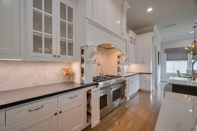 kitchen with range with two ovens, white cabinetry, ornamental molding, a chandelier, and glass insert cabinets