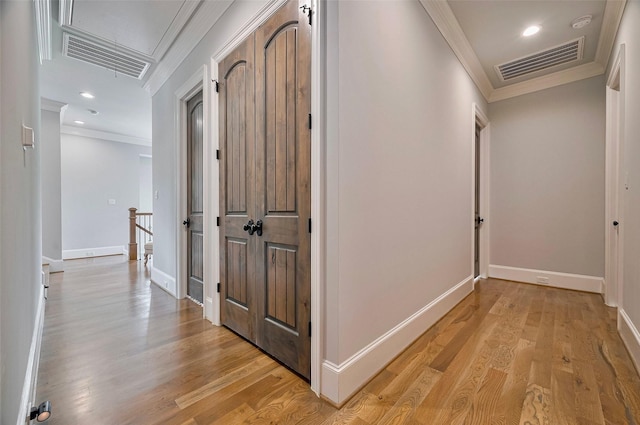 corridor featuring ornamental molding, an upstairs landing, attic access, light wood-type flooring, and baseboards