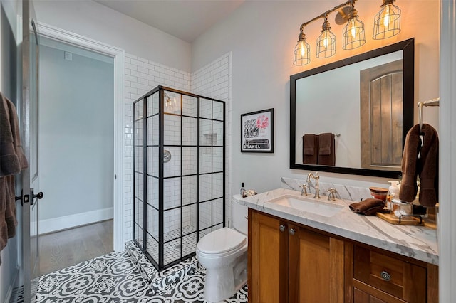 bathroom with a shower stall, toilet, vanity, and wood finished floors
