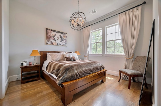 bedroom featuring baseboards, light wood-type flooring, and a chandelier