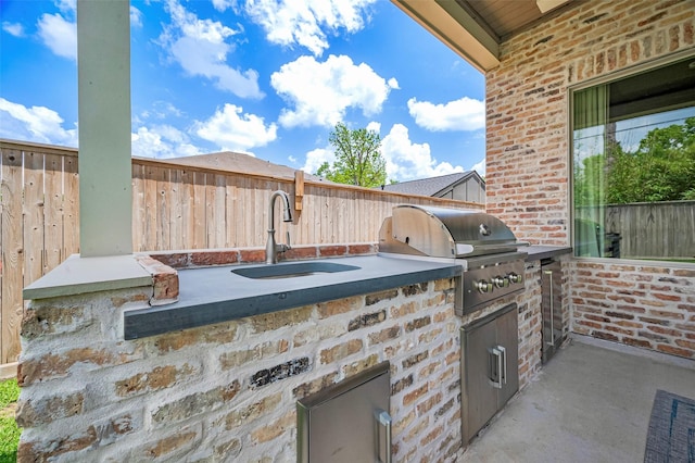view of patio / terrace with a grill, exterior kitchen, fence, and a sink