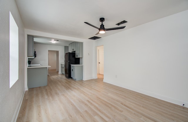 unfurnished living room with baseboards, a ceiling fan, visible vents, and light wood-style flooring