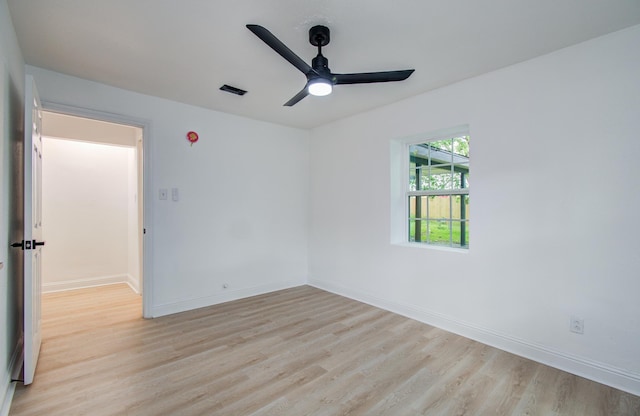 spare room with baseboards, light wood-style flooring, visible vents, and a ceiling fan