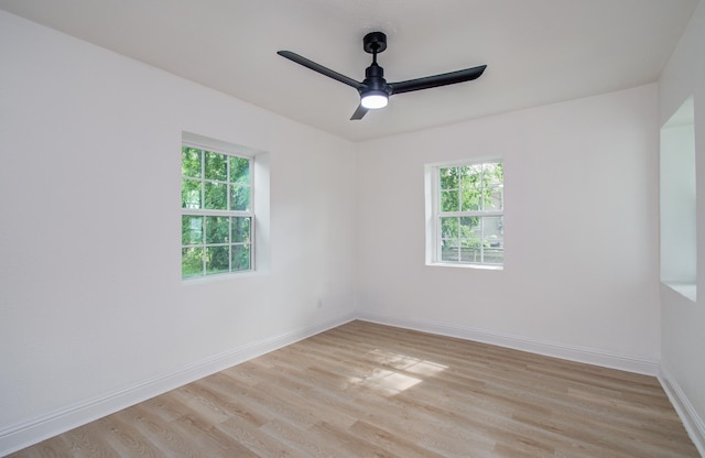 empty room with light wood finished floors, a ceiling fan, and baseboards