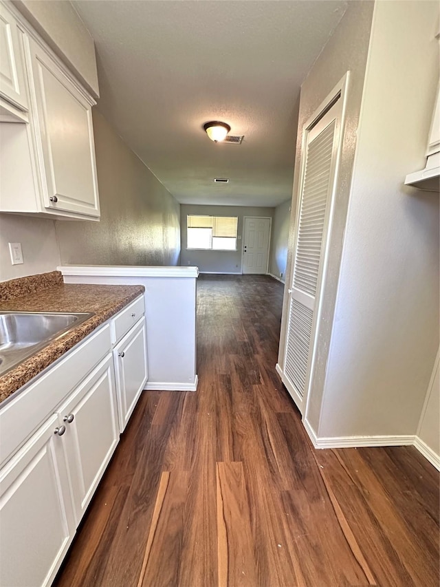 corridor featuring dark wood-type flooring and baseboards