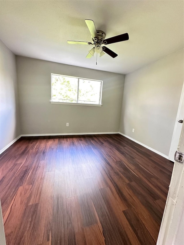 spare room with dark wood-type flooring, baseboards, and ceiling fan