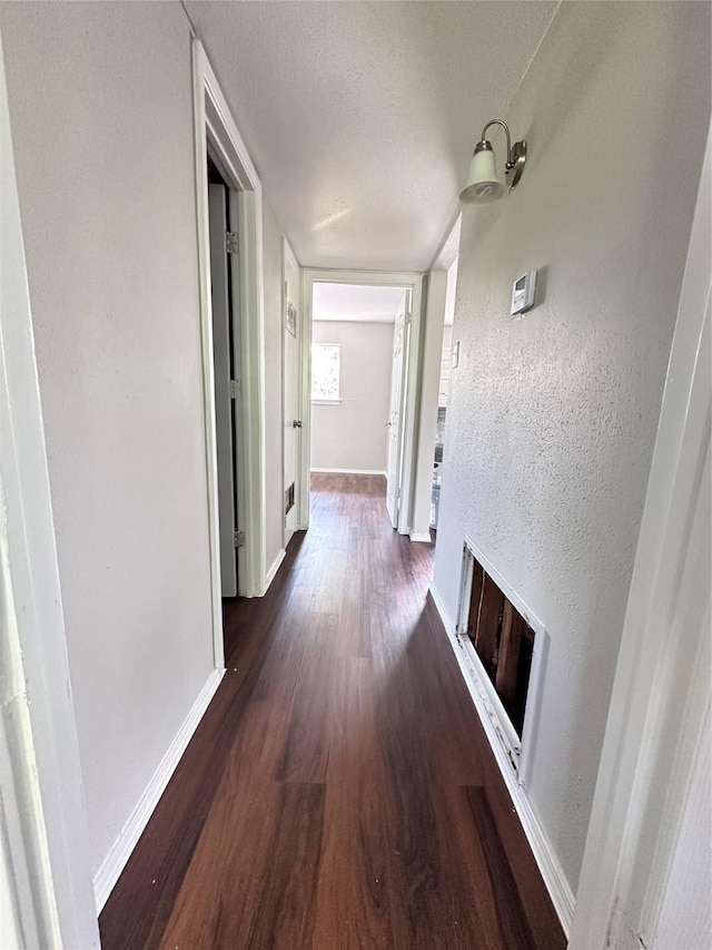 corridor with baseboards and dark wood-style floors